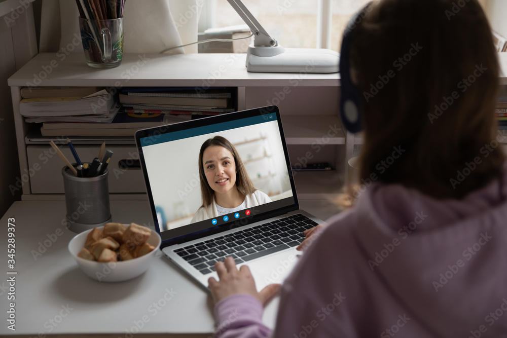 Back view of teenage girl sit at desk at home on quarantine talk on video  call
