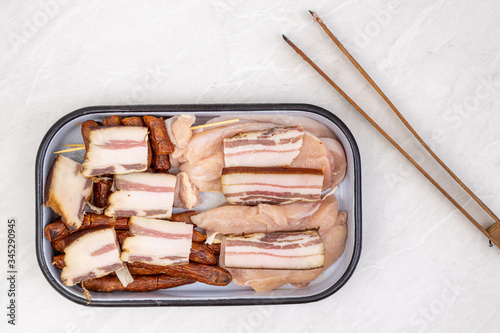 Top view of mixed meat prepared for grill. Bacon kebabs sausages and chicken breasts.