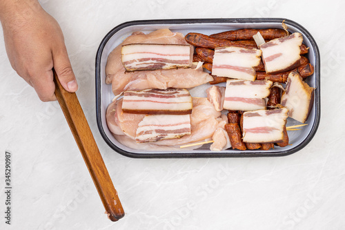 Top view of mixed meat prepared for grill. Bacon kebabs sausages and chicken breasts.