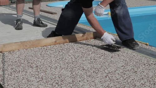 Laying the floor around the outdoor pool. The worker places a stone carpet with resin.
(Shallow DOF).