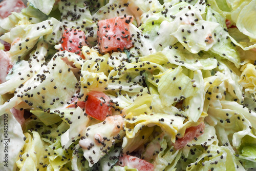 salad dressed with yogurt from onions tomatoes cucumbers iceberg lettuce sprinkled with Chia seeds . vegetable salad gluten free