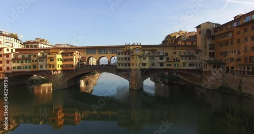 Aerial view over the Ponte Vecchio bridge. Most ancient bridge of the city of Florence under the clear blue sky on a sunny day. Arno river reflects the buildings on the banks. Italy. Apr 2016