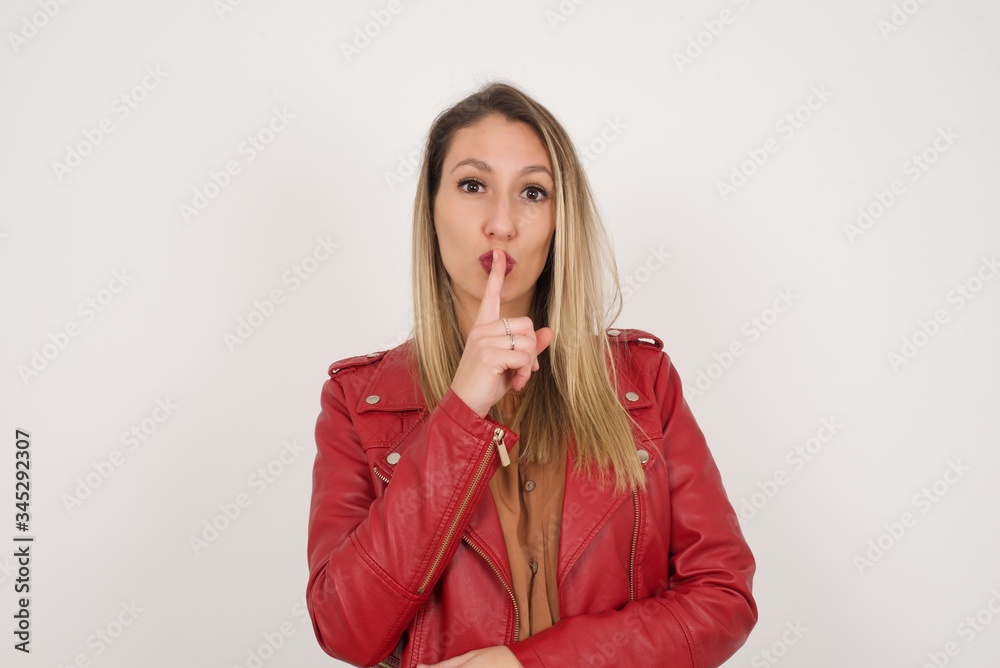 Dont tell my secret or not speak too loud, please! Emotional surprised student makes hush gesture, asks be quiet, has scared expression as afraids of revealing secret, poses against gray studio wall. Dont tell my secret or not speak too loud, please! Emotional surprised student makes hush gesture, asks be quiet, has scared expression as afraids of revealing secret, poses against gray studio wall.