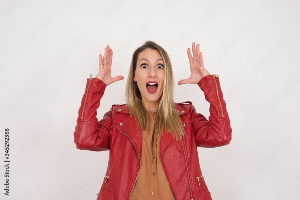 Portrait of beautiful brunette female looks with excitement at camera, keeps hands raised over head, notices something unexpected, isolated over gray wall. Lovely woman reacts on sudden news. Portrait of beautiful brunette female looks with excitement at camera, keeps hands raised over head, notices something unexpected, isolated over gray wall. Lovely woman reacts on sudden news.