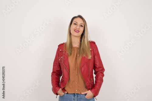 Young beautiful woman over isolated background happy face smiling with hands in pockets looking at the camera. Positive person.