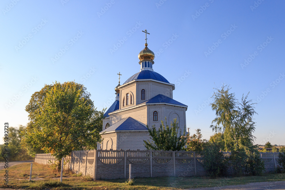 Orthodox church in the village, rural summer landscape. In the evening, before sunset. The concept of religious architecture, Easter, other holidays and various religious denominations in Ukraine. Orthodox church in the village, rural summer landscape. In the evening, before sunset. The concept of religious architecture, Easter, other holidays and various religious denominations in Ukraine.