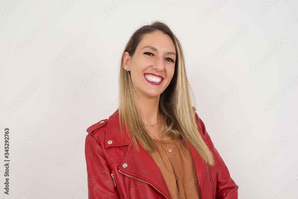 Shy girl smiling looking to the camera. Caucasian charming girl sanding against gray studio background feeling shy. Shy girl smiling looking to the camera. Caucasian charming girl sanding against gray studio background feeling shy.