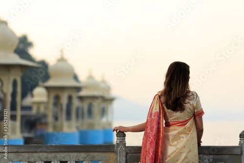 A woman wearing saree is watching the sunrise and flying birds in Udaipur the most romantic place in India.