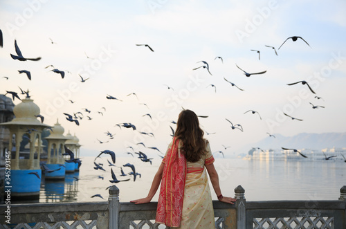 A woman wearing saree is watching the sunrise and flying birds in Udaipur the most romantic place in India.