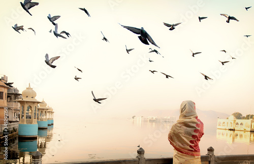 A woman wearing saree is watching the sunrise and flying birds in Udaipur the most romantic place in India.