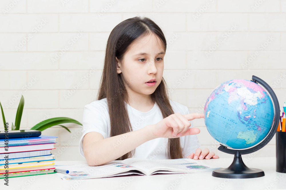 Distance learning online education. A schoolgirl is studying at home and doing homework. Sitting at the table with textbooks Distance learning online education. A schoolgirl is studying at home and doing homework. Sitting at the table with textbooks