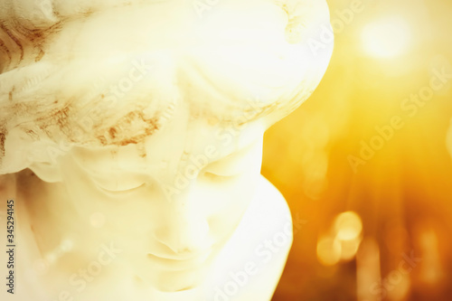 Fototapeta Naklejka Na Ścianę i Meble -  Fragment of ancient stone statue of beautiful white guardian angel in sun rays