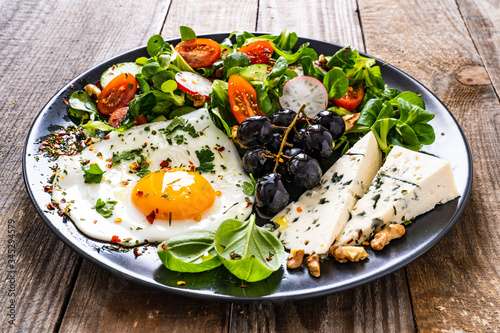 Continental breakfast - sunny side up egg, blue cheese, grapes and vegetable salad 