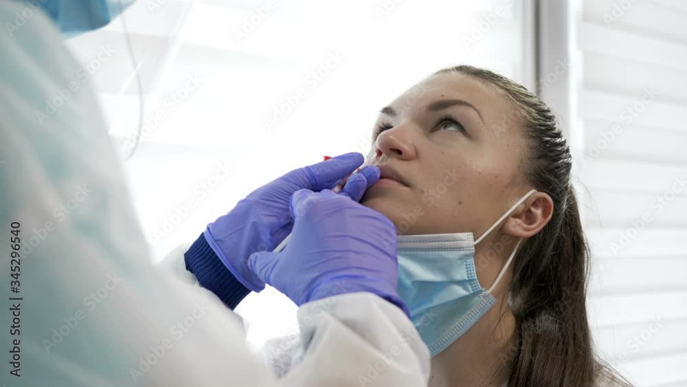 Nasal vaccination. Nurse in a protective suit administers a vaccine through a nose to a young patient. Covid-19. Nasal vaccination. Nurse in a protective suit administers a vaccine through a nose to a young patient. Covid-19.