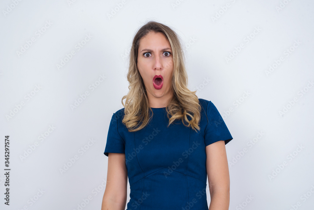 Expressive facial expressions. Shocked stupefied female, keeps jaw dropped, feels stunned from what she sees aside on blank gray Wall Expressive facial expressions. Shocked stupefied female, keeps jaw dropped, feels stunned from what she sees aside on blank gray Wall