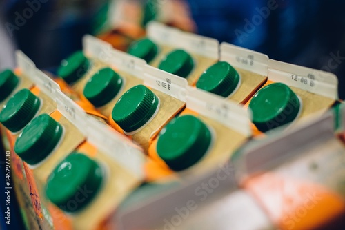Selective focus shot of lines of orange juice cartons with green locks