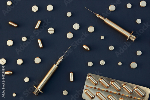 Gold tablets and syringes on a dark background.