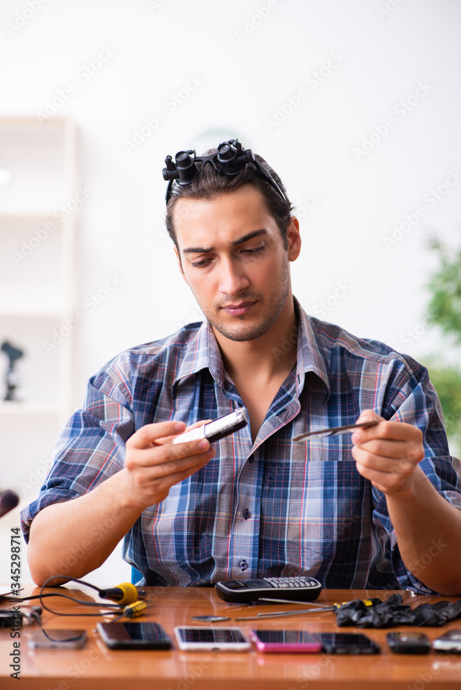 Young male technician repairing mobile phone Young male technician repairing mobile phone