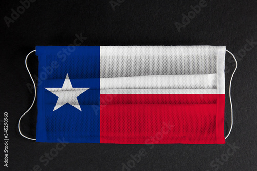 Coronavirus Covid-19 in Texas U.S. state. Flag of the State of Texas printed on medical mask on black background. Coronavirus update in Houston. State healthcare concept.
 photo