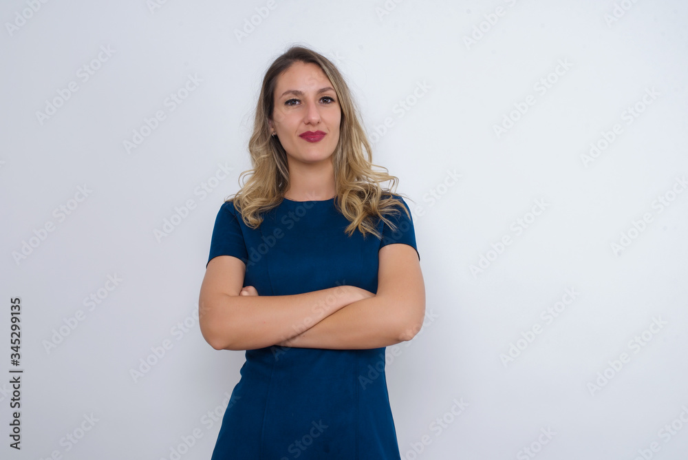 Waist up portrait of beautiful young female with positive expression, has crossed arms, feels happy and confident, wears casual clothes, isolated over gray background Waist up portrait of beautiful young female with positive expression, has crossed arms, feels happy and confident, wears casual clothes, isolated over gray background
