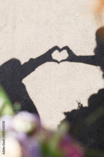 Shadow heart made on the asphalt from the hands