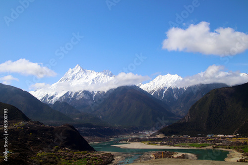 Fototapeta Naklejka Na Ścianę i Meble -  The Nanjiabawa Peak, which is hidden in the mountains and wild peach blossoms, is even more precipitous against the blue sky, white clouds, and green water!