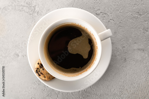 black coffee in a white cup with cookies on a gray background