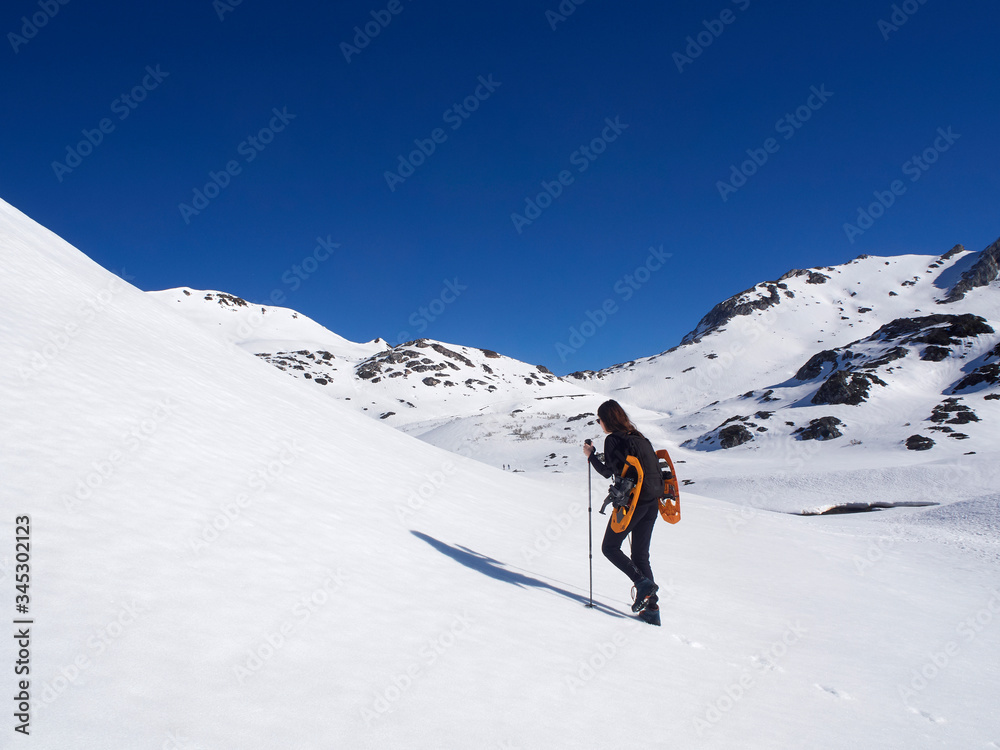 Woman snowshoeing in San Isidro, León, Spain on a sunny day. Blue sky. White snow. Women's empowerment. Female power