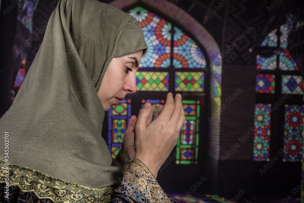 Muslim woman praying for Allah muslim god at room near window. Hands of muslim woman on the carpet praying in traditional wearing clothes, Woman in Hijab, Carpet of Kaaba, Selective focus, toned