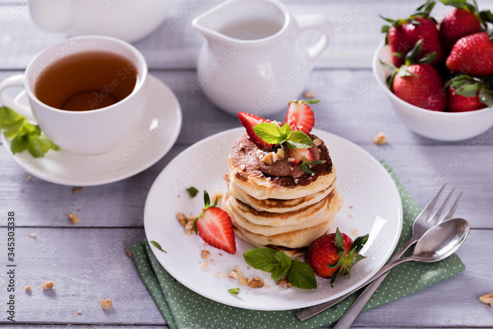 Pancakes with chocolate sauce and fresh strawberries on white wooden background. Delicious sweet dessert. Pancakes with chocolate sauce and fresh strawberries on white wooden background. Delicious sweet dessert.