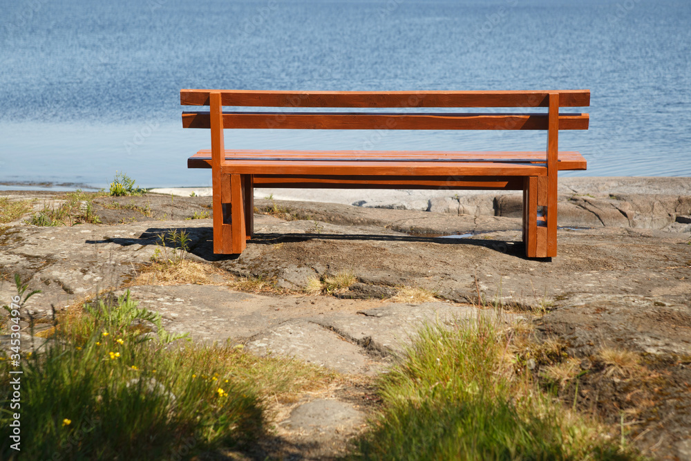 A wooden bench on the shore of Ladoga on the island of Valaam on a sunny day.