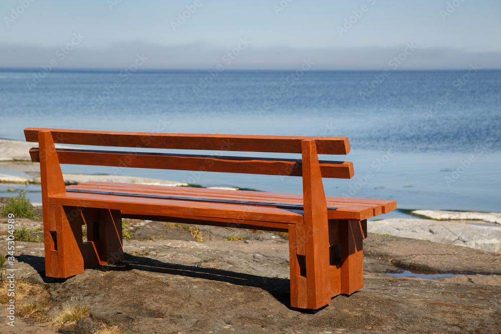A wooden bench on the shore of Ladoga on the island of Valaam on a sunny day.