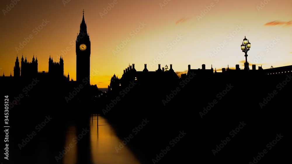 Silhouette view of the Houses of Parliament and the Big ben Tower in London with a yellow sky at sunset. Panoramic format.