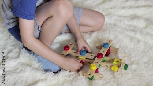 A little boy collects a plane from a wooden designer on a fluffy bedspread. Children's educational games