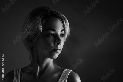 Female portrait close-up looks away, black and white photo dark