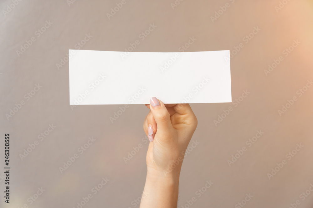 closeup on a light background a womans hand holds white paper for text inscription