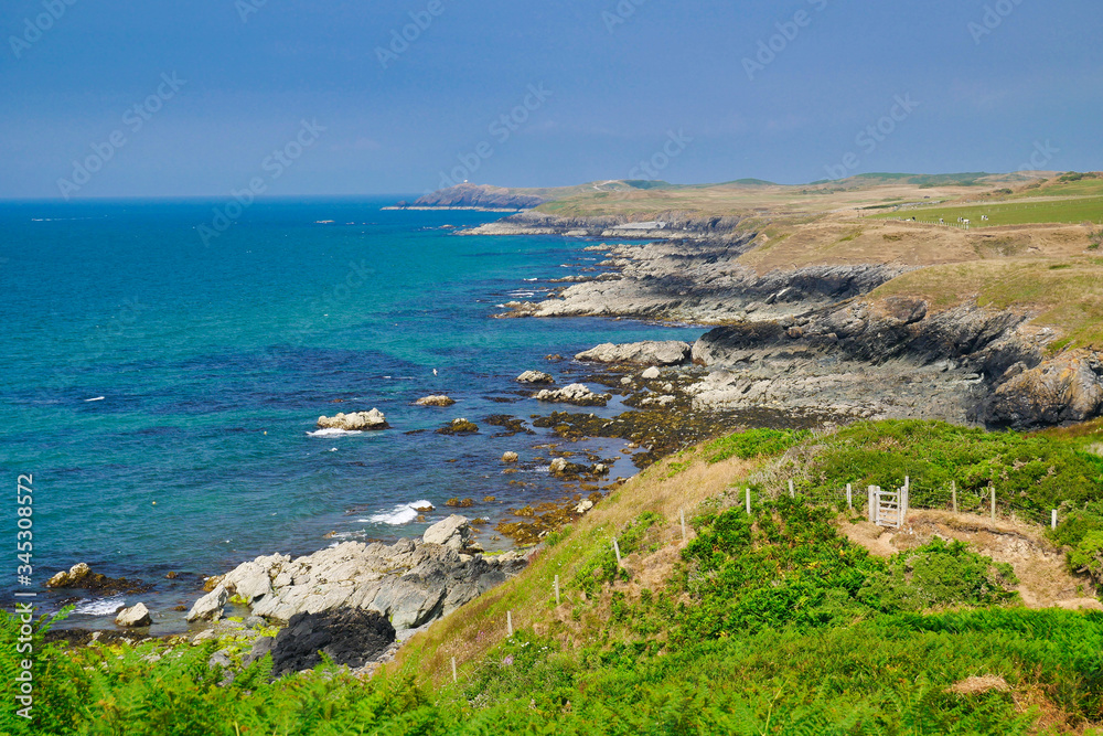 The rugged, rocky coastline of the northern Llyn Peninsula in Wales UK, showing the clear blue sea and with the coast path in the foreground. Taken on a sunny day with blue skies in summer.