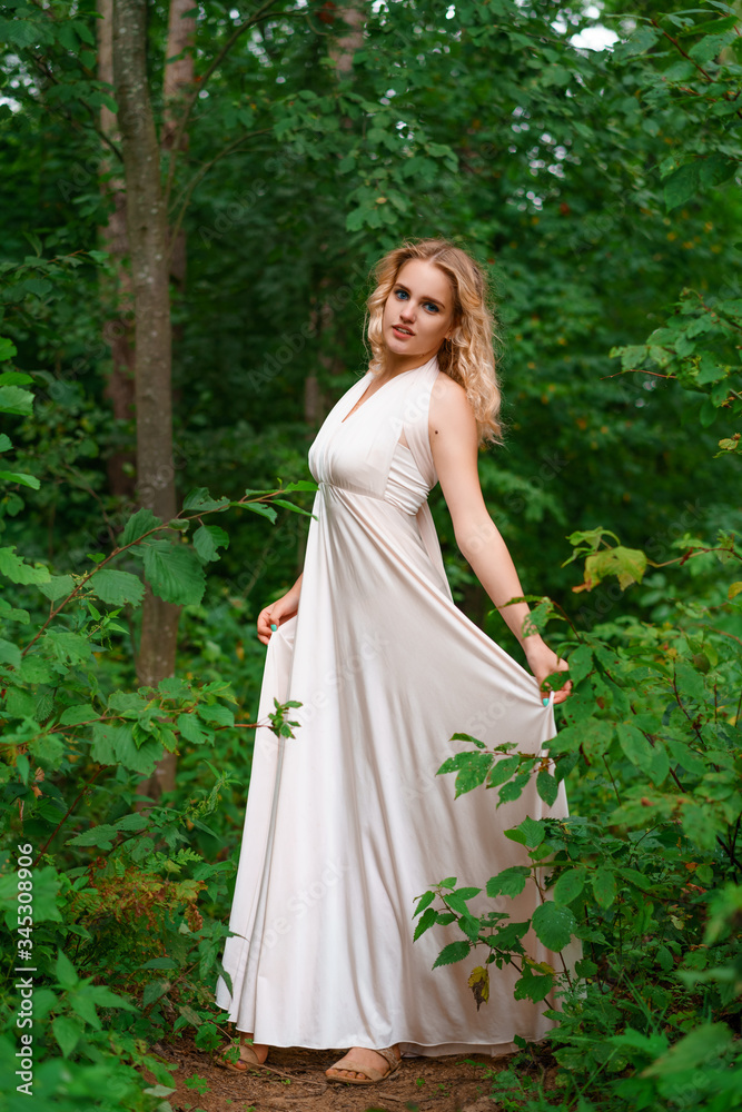 Young woman poses in a pink dress in the forest