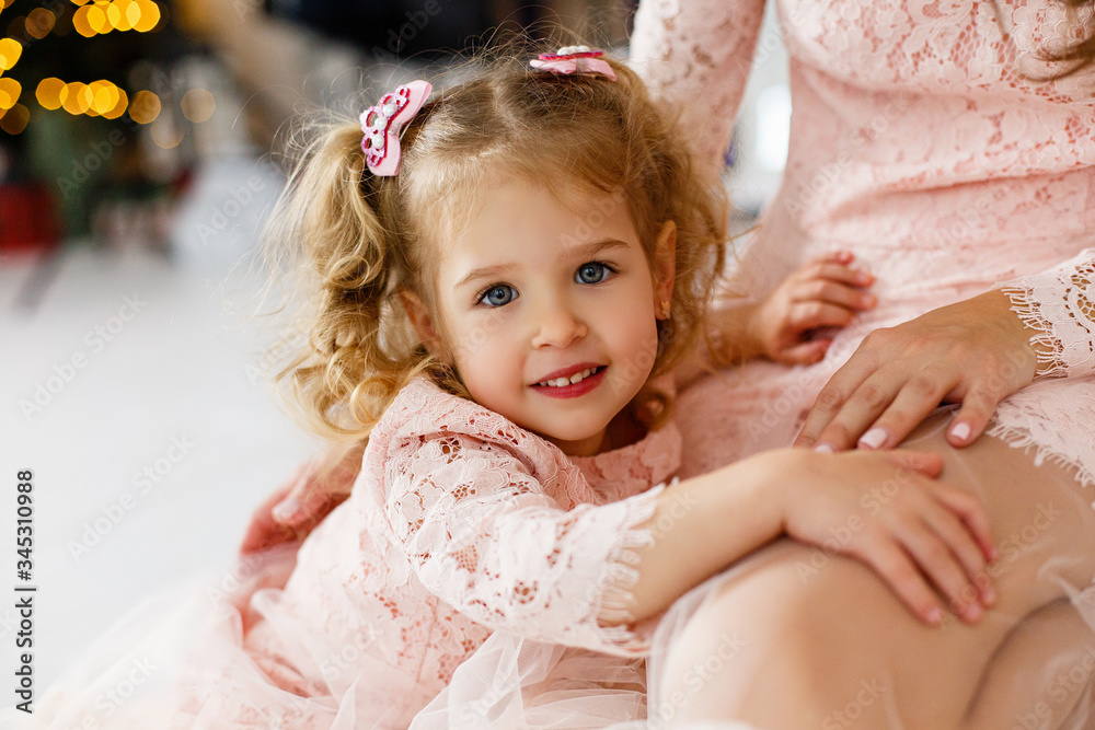 Portrait of little girl lying on mother's knees. Happy family having fun together at home. Family relationship concept. Stay home. Isolation together. Cozy home. Parents spending time with kid at home Portrait of little girl lying on mother's knees. Happy family having fun together at home. Family relationship concept. Stay home. Isolation together. Cozy home. Parents spending time with kid at home