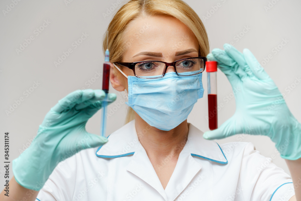 Doctor or woman nurse wearing protective mask holding syringe and blood test tube Doctor or woman nurse wearing protective mask holding syringe and blood test tube