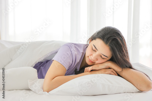 Sleeping girl lying on the white bed on her comfy pillow in the morning with copy space