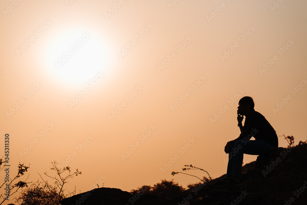 Silhouette of an Indian man sitting in front of the sunset at Wankaner, Gujarat, India