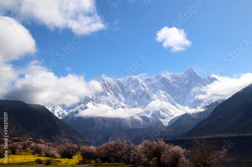 Through the mountains and wild pink peach blossoms, looking at Nanjiabawa Peak, against the blue sky, white clouds, and green water, it is even more steep and majestic!