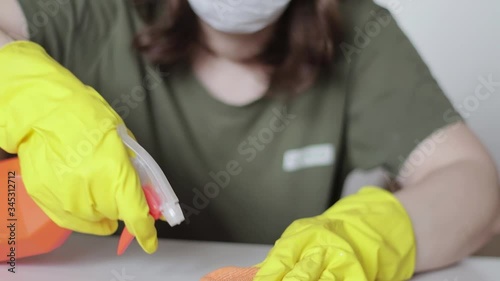 A woman in rubber gloves wipes a furniture surface with a sanitizer. House surface disinfection. Close-up