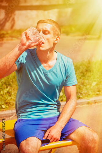 Sport, health and lifestyle concept. Young athletic man after training drinking water from bottle. Vertical image.