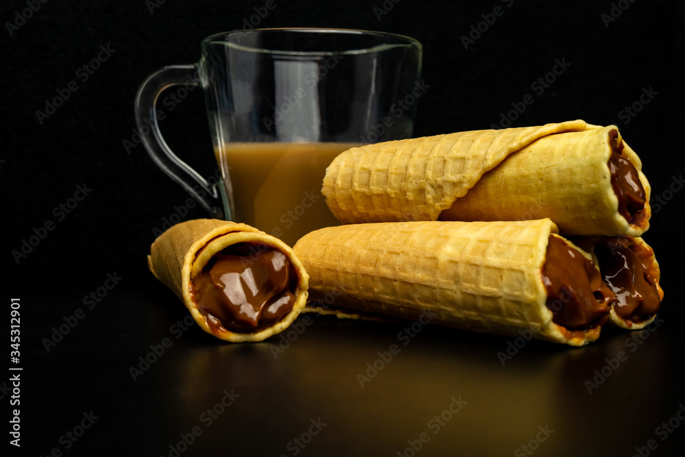 Wafer rolls with condensed milk on a white plate.