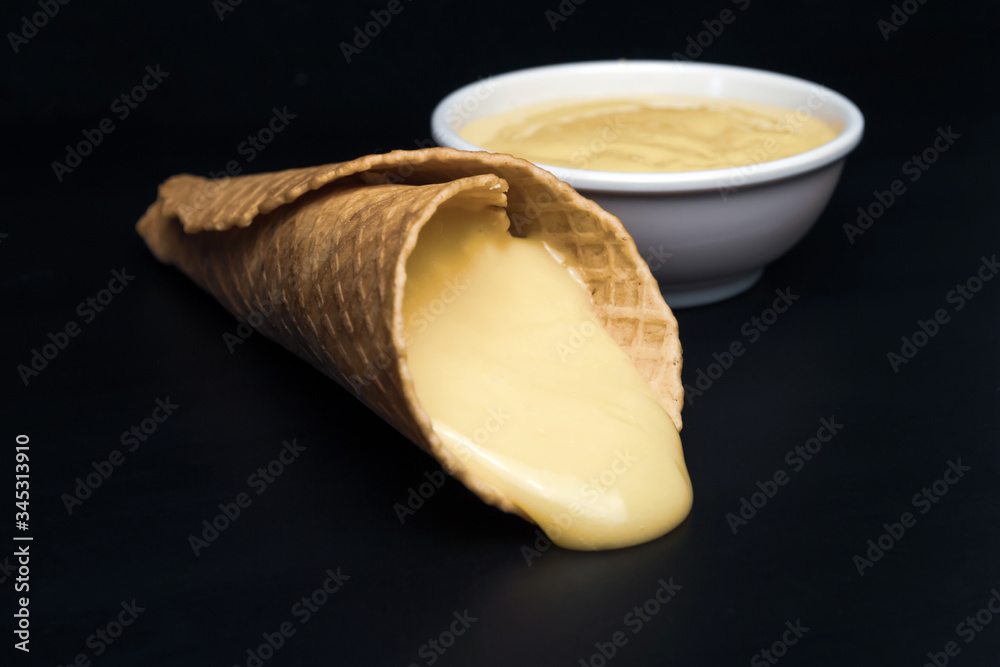 Wafer rolls with condensed milk on a white plate.