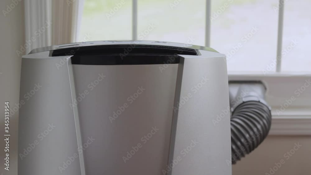 Portable air conditioner in front of brightly lit window.