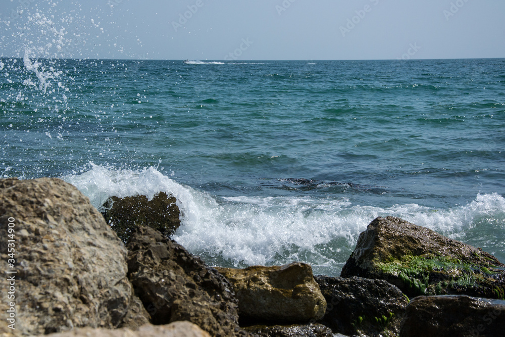 Beautiful wild beach landscape, sunny day, water waves hitting the cliffs, nature summertime scene Beautiful wild beach landscape, sunny day, water waves hitting the cliffs, nature summertime scene