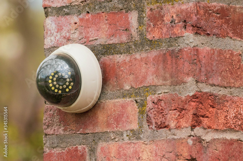 Fake security camera on the wall outside. security camera on a brick pillar in the yard.